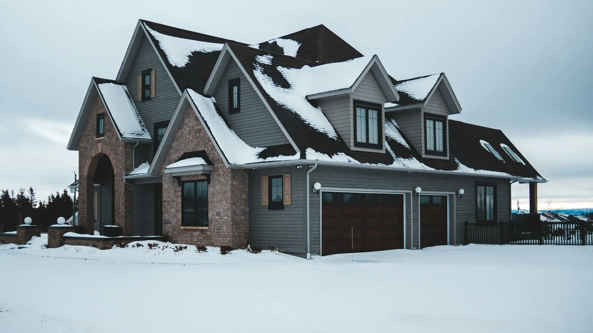 A new two-storey home with an attached garage on a snow-covered lot